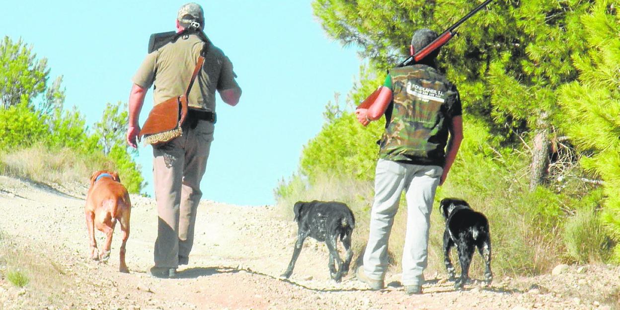 Dos cazadores regresan con sus perros de una jornada de caza de perdiz en el puerto de la Cadena de Murcia.