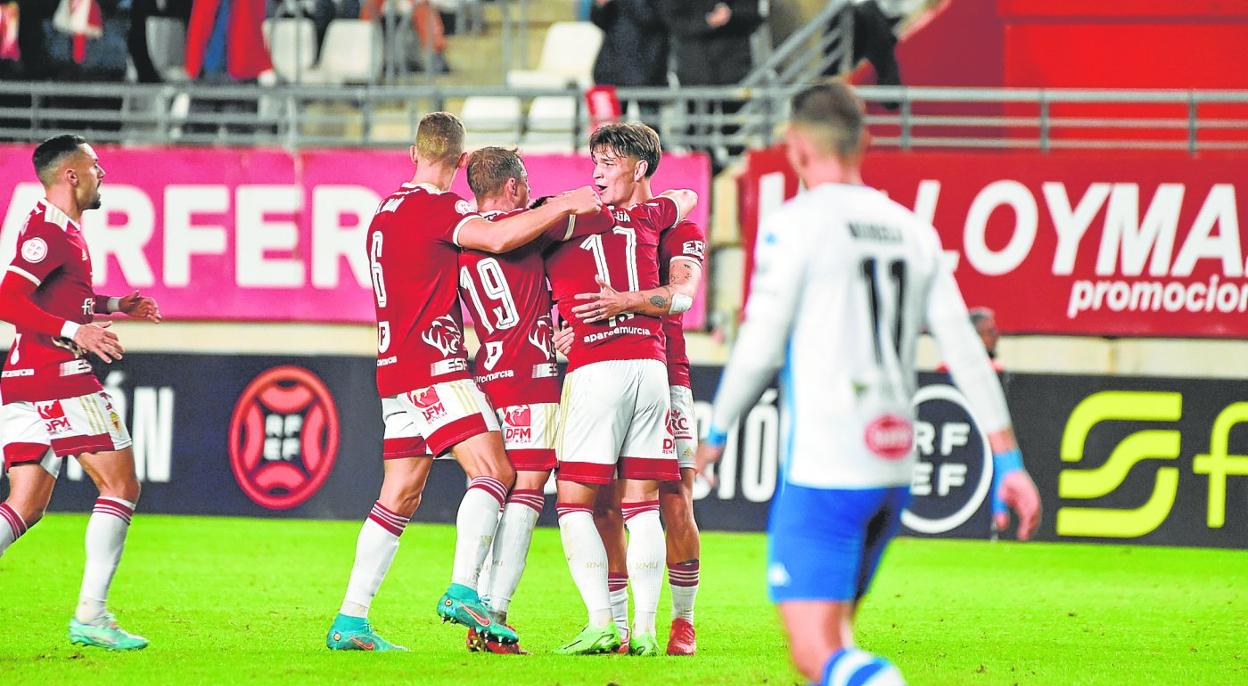 Los jugadores del Real Murcia felicitan a Dani Vega, autor del gol que dio el triunfo al Real Murcia ante el Alcoyano en el estadio Enrique Roca, el pasado domingo. 
