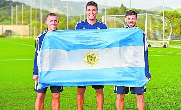 Los tres argentinos de la primera plantilla, De Blasis, Musto y Franchu, posan con la bandera de su país tras el título Mundial de Qatar, ayer en La Manga Club. 