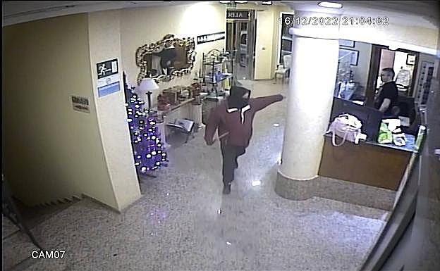 Momento de la grabación de la cámara de seguridad en el que el atacante amenaza al recepcionista del hotel. 