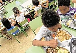 Varios menores comen en un centro escolar.