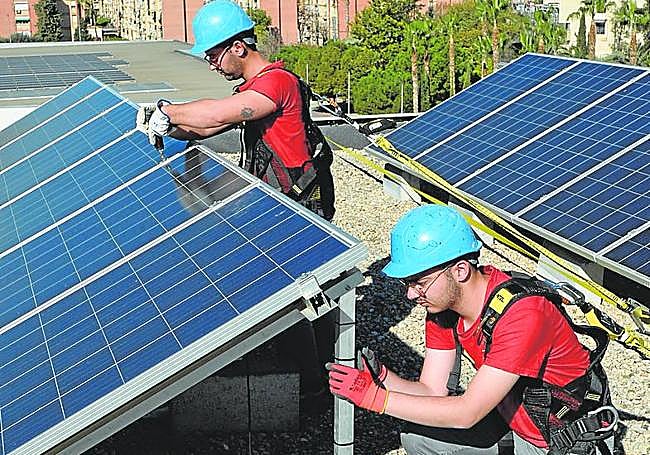 Dos alumnos colocan placas en el doble techo del Aulario Peridis.