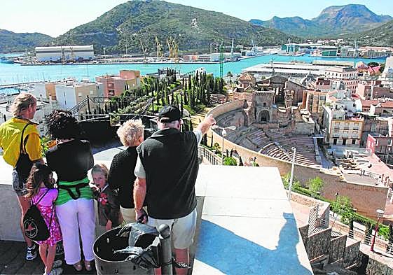 Un grupo de turistas observa el Teatro Romano y la dársena del puerto desde el mirador del Parque Torres.