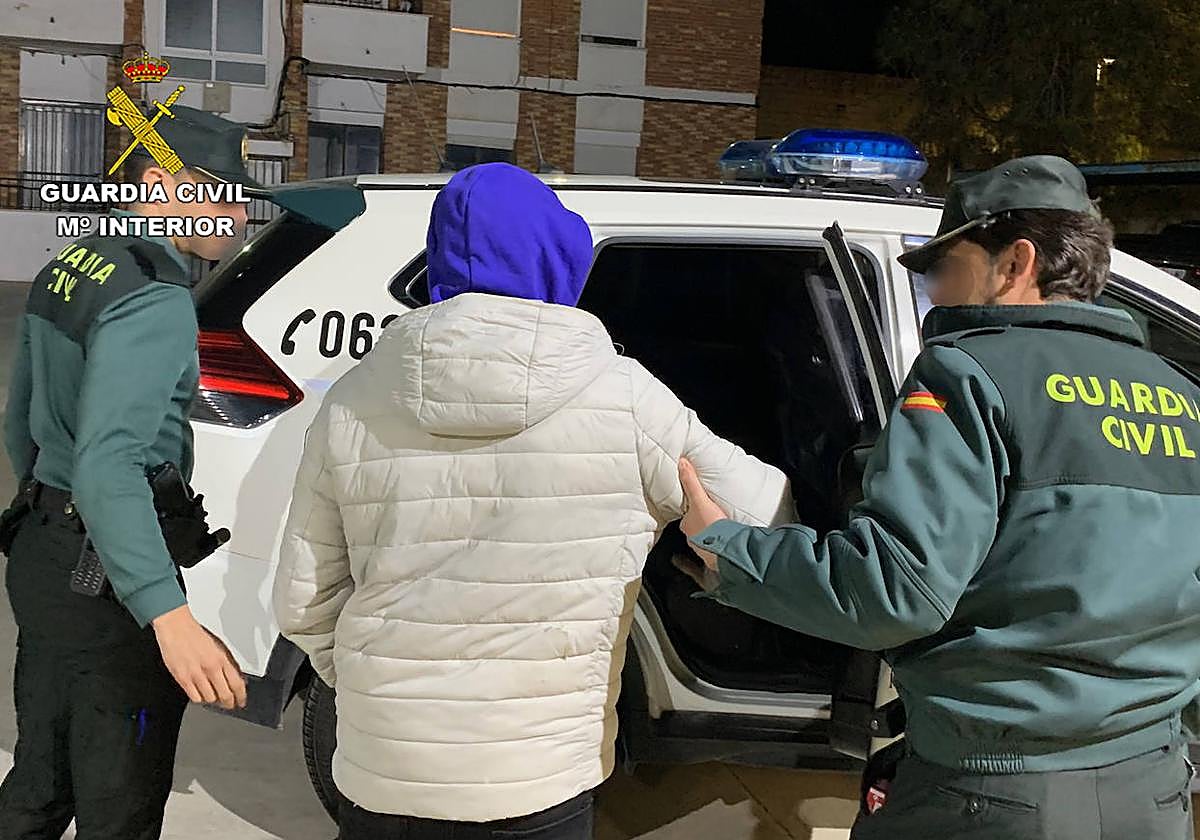 Dos guardias civiles acompañan al detenido al coche.