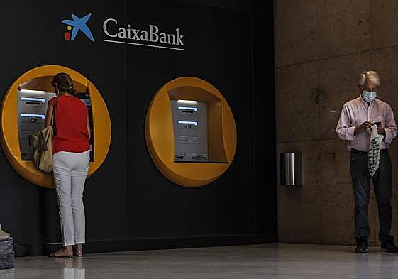 Una mujer saca dinero del cajero del banco.