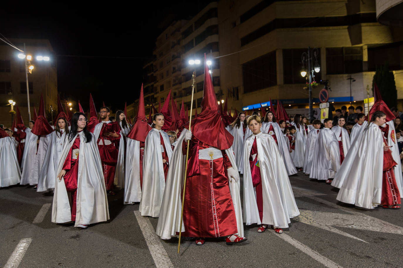Grupo de niños nazarenos comienza a vaciar sus bolsas cargadas de dulces entre los asistentes.