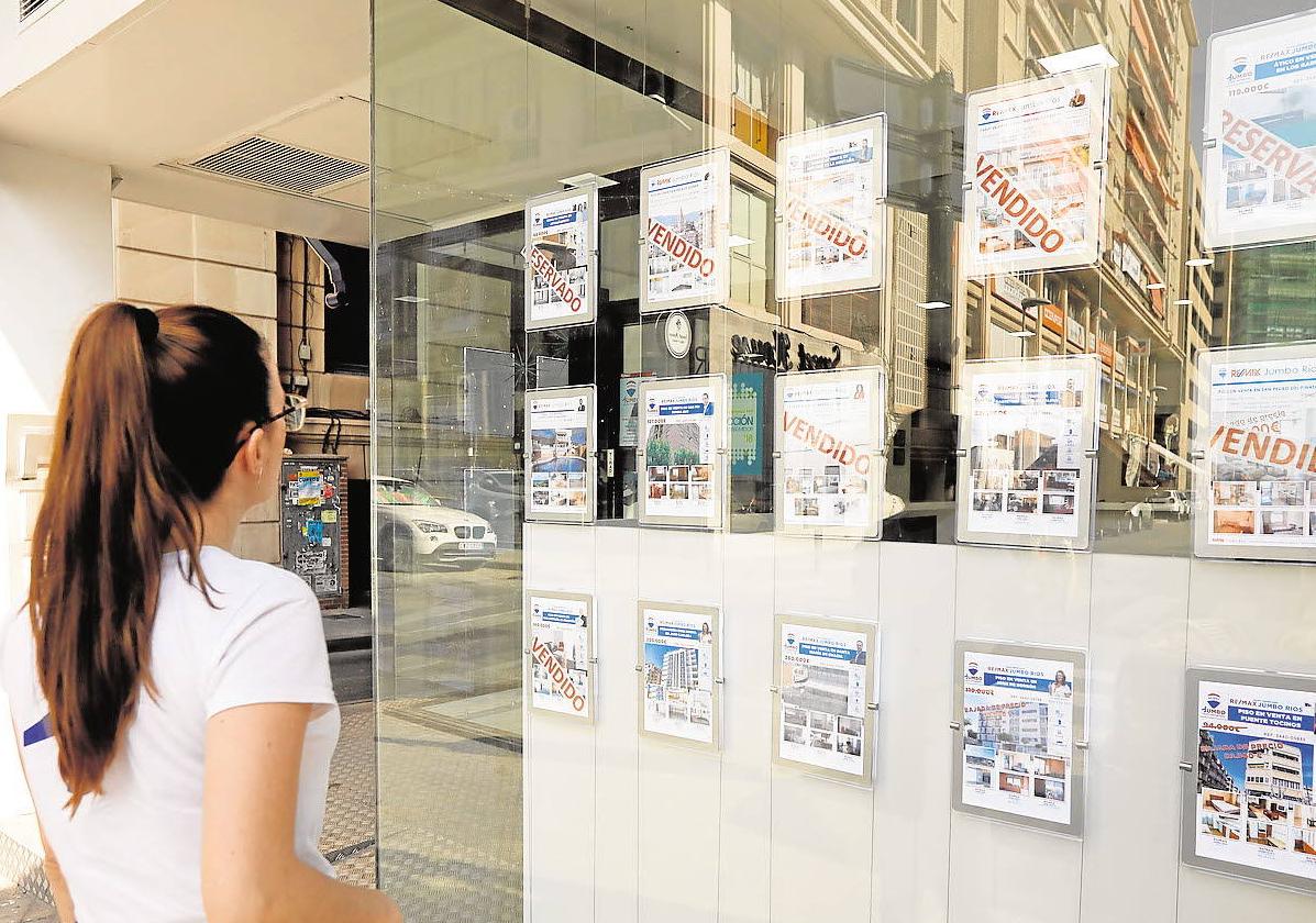 Una joven visualiza los carteles de una inmobiliaria, en una imagen de archivo.