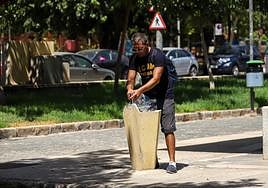 Un hombre llena una garrafa de agua en una fuente de agua en Murcia.