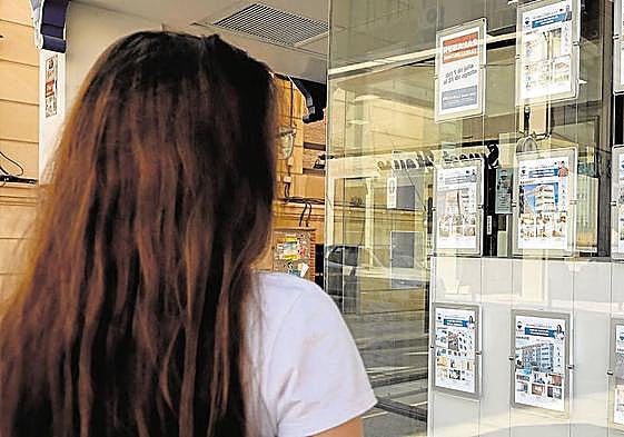 Una joven estudia las ofertas de una inmobiliaria en Murcia.