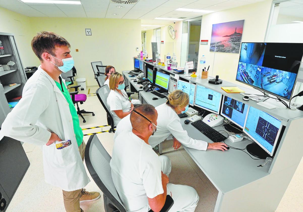 Juan Antonio Encarnación (de pie) e Isabel de la Fuente (consultando el monitor), siguen una sesión de radioterapia desde la sala de control, la semana pasada.