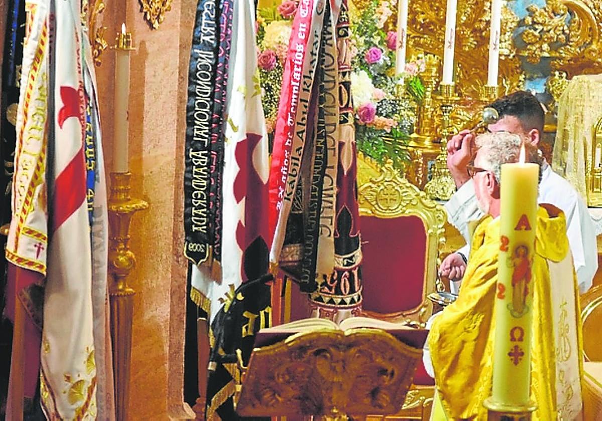 El rector de la Basílica bendice las banderas, ayer.