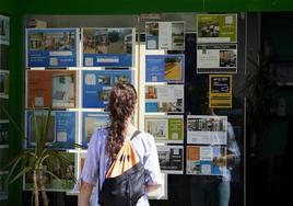 Una joven observa el escaparate de una inmobiliaria, en una foto de archivo.