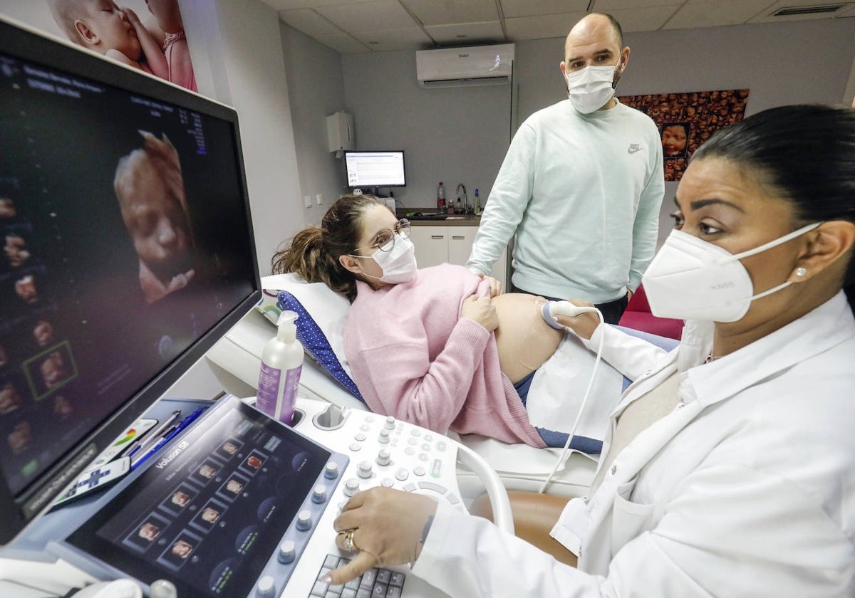 Una ginecóloga realiza una ecografía a una mujer embarazada.