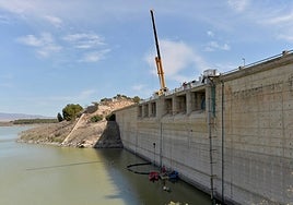 Operarios, con una lancha y un grúa de gran tonelaje, en la presa de Santomera.