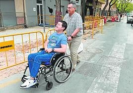 Fernando empuja la silla de ruedas de su hijo por una vía reservada a los coches en el barrio del Infante Juan Manuel.