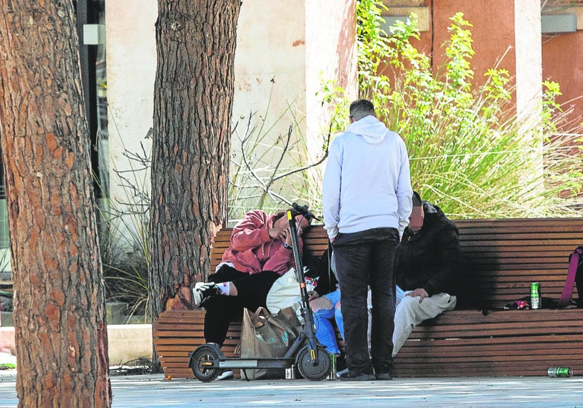 Un grupo de personas en los bancos de la plaza Juan XXIII junto a unas latas de cerveza.