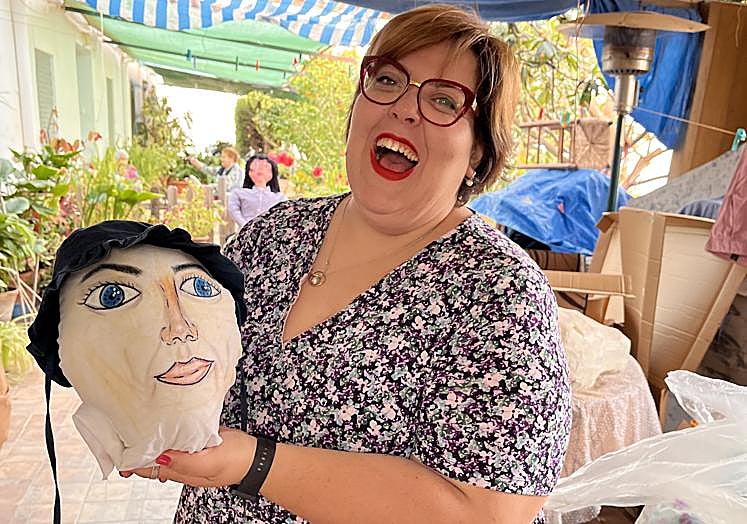 La vecina muestra con alegría cómo van quedando las facciones humanas en la cabeza del mayo.