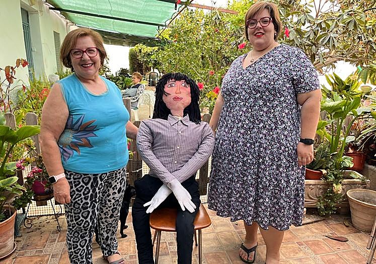 Inés Egea e Inés Serrano, una vez finalizado el mayo, instalan el pelele en una silla para comenzar a colocarle la vestimenta que tienen preparada para él.