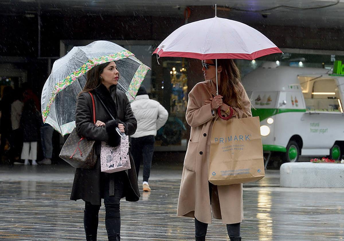 Dos personas transitan con paraguas por las calles de Murcia, en una imagen de archivo.
