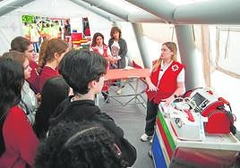 Una voluntaria de Cruz Roja muestra a varios jóvenes material sanitario de la ONG, ayer en Murcia.