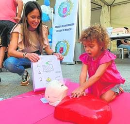Una niña aprende a realizar un masaje cardíaco bajo la supervisión de una enfermera, durante el Día de la Enfermería, celebrado en la plaza de Santo Domingo, en Murcia.