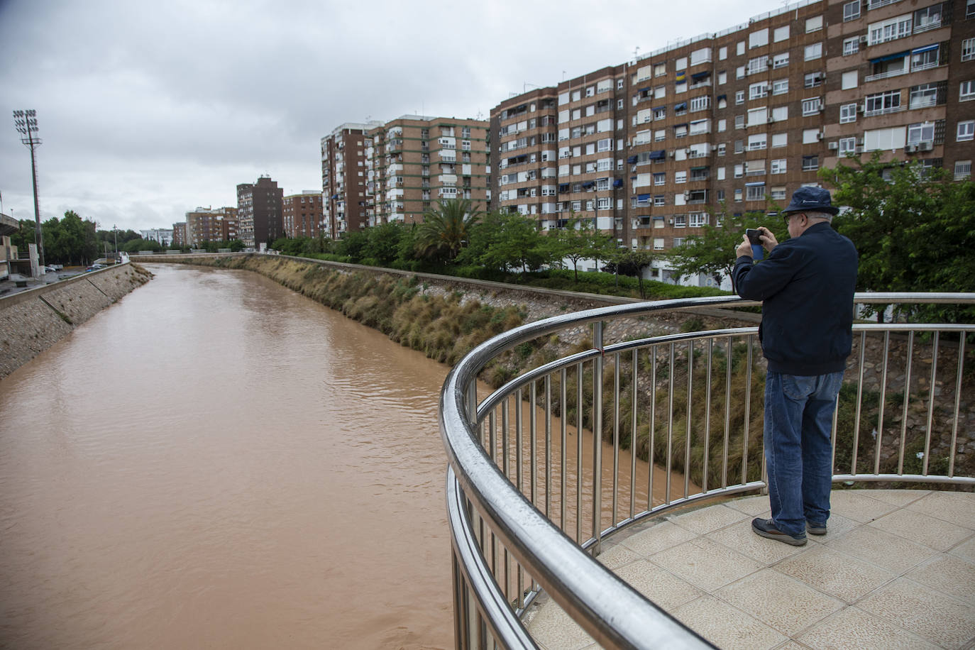 Un hombre fotografía la rambla de Benipila cargada tras las lluvias.