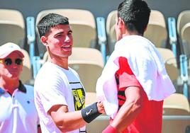 Carlos Alcaraz saluda a Novak Djokovic antes de su entrenamiento de ayer en Roland Garros.