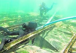 Arqueólogos examinan el barco fenicio de Mazarrón, dentro de su 'sarcófago' y cubierto de arena.