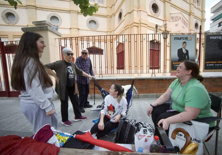 Las jóvenes explican a unos viandantes el motivo por el que hacen la cola.