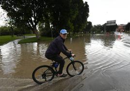 Un vecino de La Alberca recorre en bici una de las zonas inundadas, ayer, por las lluvias.