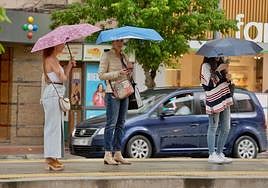 Tres mujeres se resguardan de la lluvia bajo sus paraguas en Murcia.