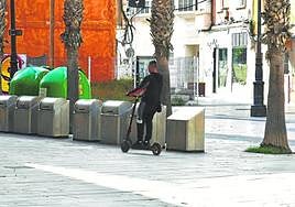 Un joven en un patinete eléctrico circulando por la Plaza José María Artes, en un lateral del Palacio Consistorial.