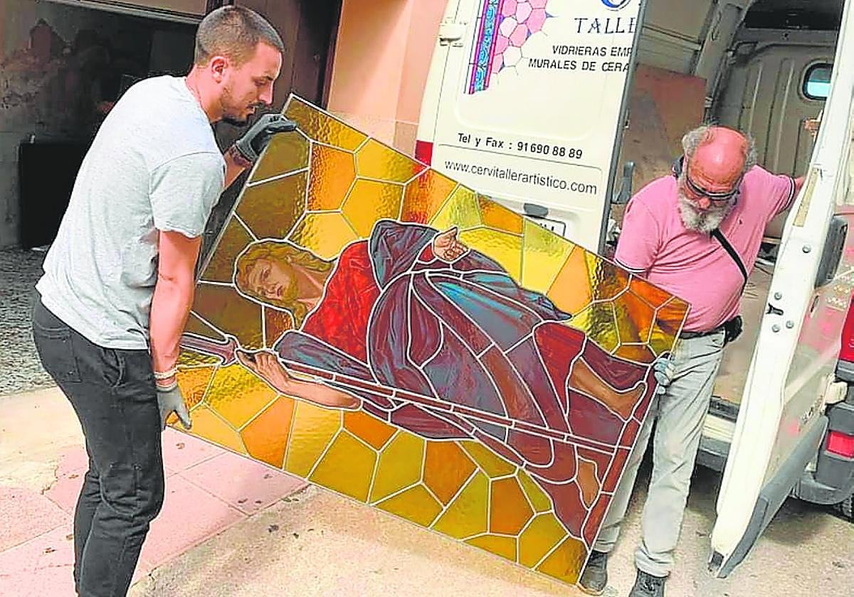 Dos operarios trasladan una de las nuevas vidrieras.