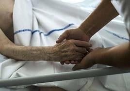 Un sanitario arropa a un paciente de cuidados paliativos, en una imagen de archivo.