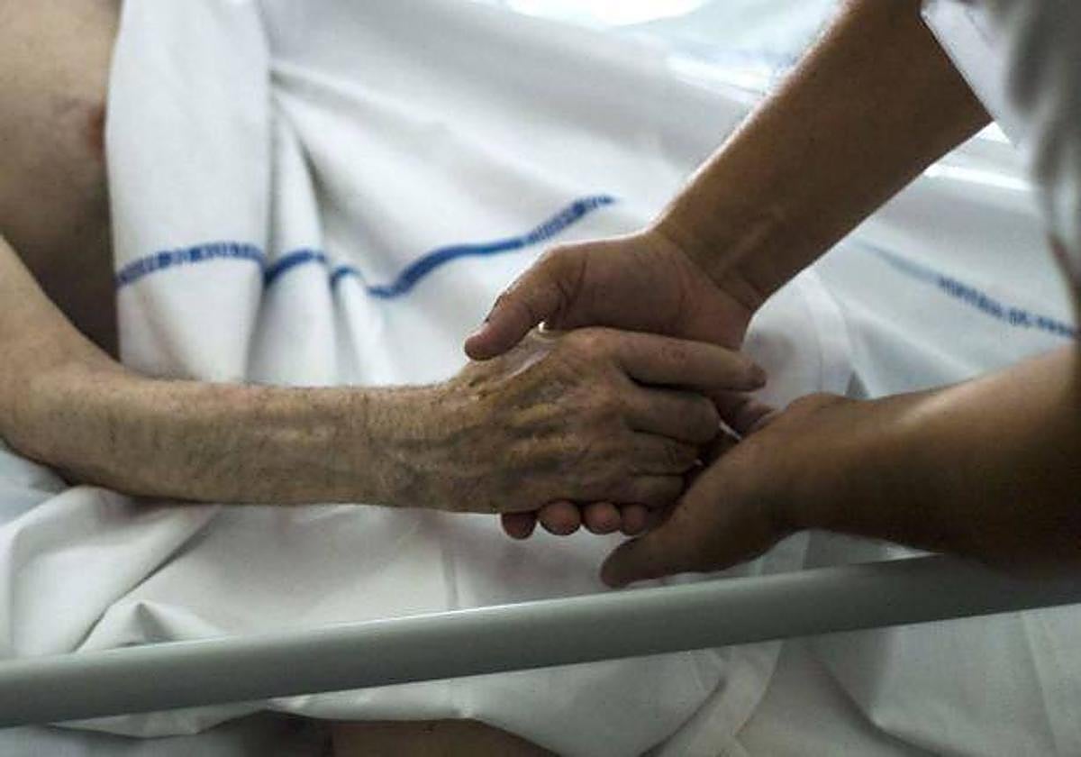 Un sanitario arropa a un paciente de cuidados paliativos, en una imagen de archivo.