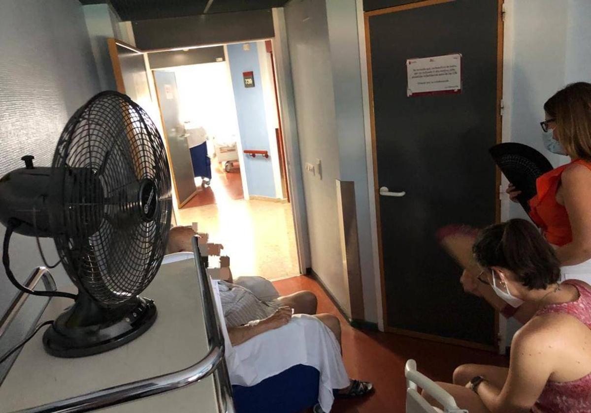 Acompañanentes de uno de los pacientes de La Arrixaca utilizan abanicos para aguantar el calor.