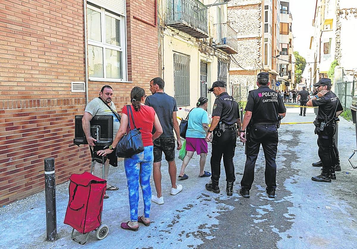 Algunos de los residentes del edificio sacan sus pertenencias vigilados por agentes municipales y nacionales.