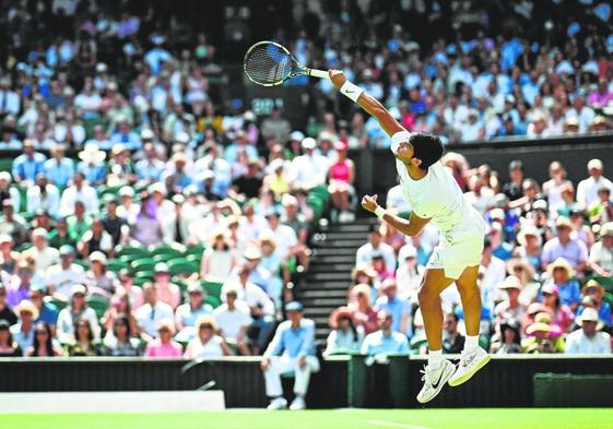 Carlos Alcaraz sirve en su partido de segunda ronda ante el francés Muller, ayer en la pista central del All England Club de Londres.