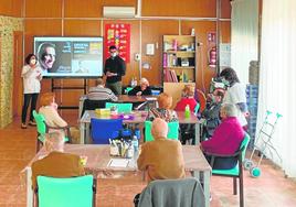 Los usuarios realizan un taller de estimulación cognitiva acompañados de una profesional del centro.