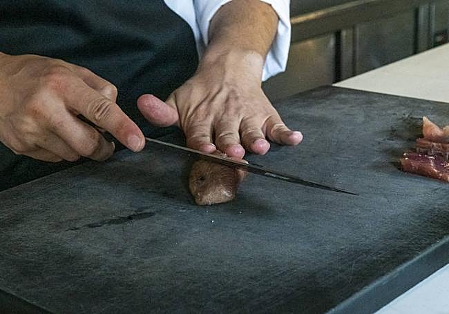 Adrián Costa corta la baconeta lista para su consumo tras refrescarla.