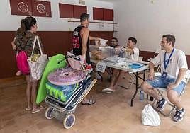 Un hombre deposita su voto en una urna acompañado por su familia, tras darse un baño en la playa de Bolnuevo, Mazarrón.