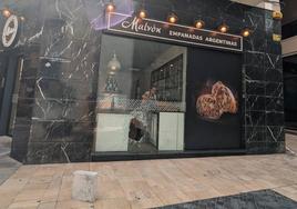 Agujero en el escaparate de empanadas Malvón por el que accedieron al interior del local para robar este jueves.