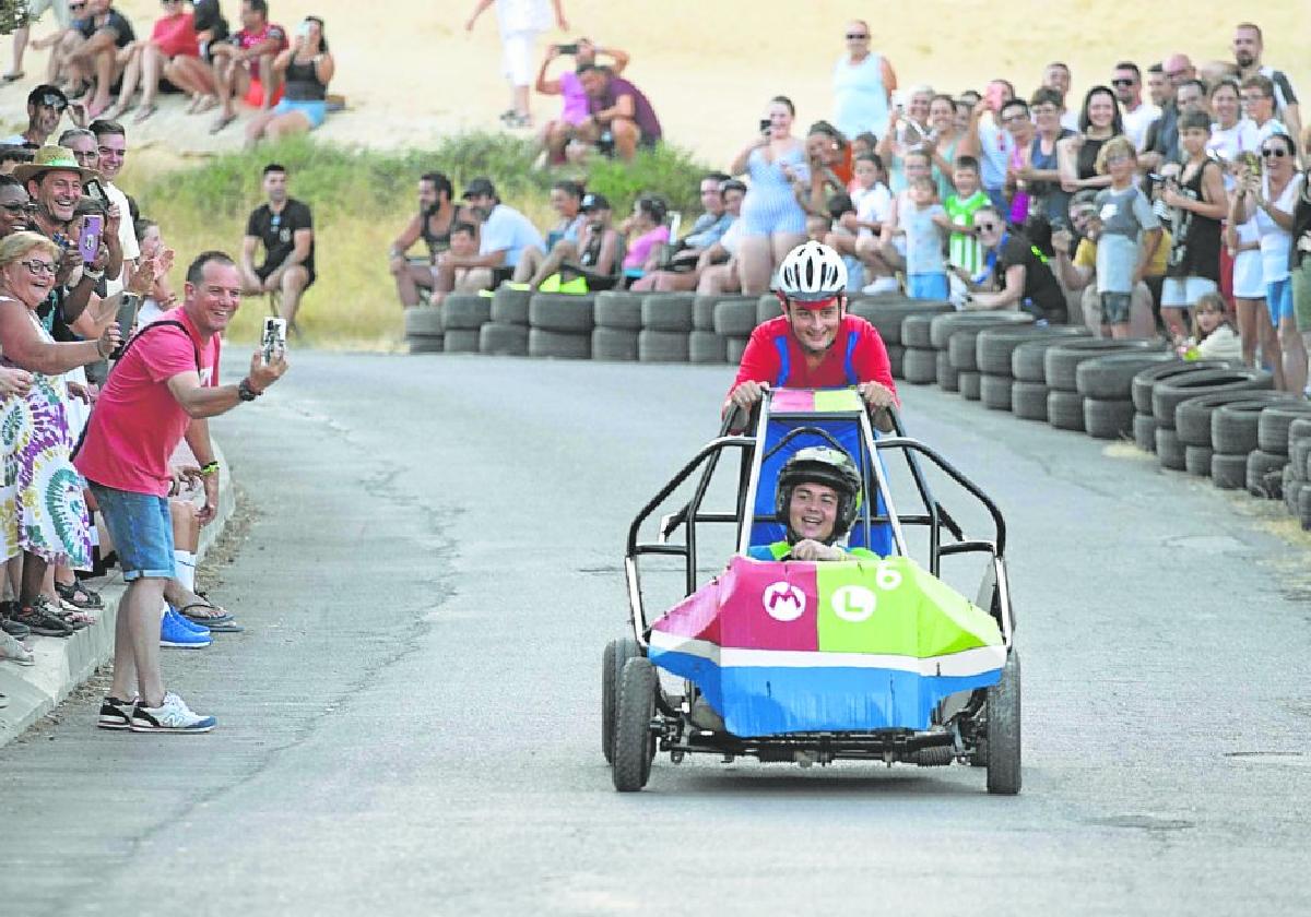 El público anima a dos jóvenes que recorren con su auto el camino del cementerio hacia la iglesia, ayer en las fiestas de Canteras.