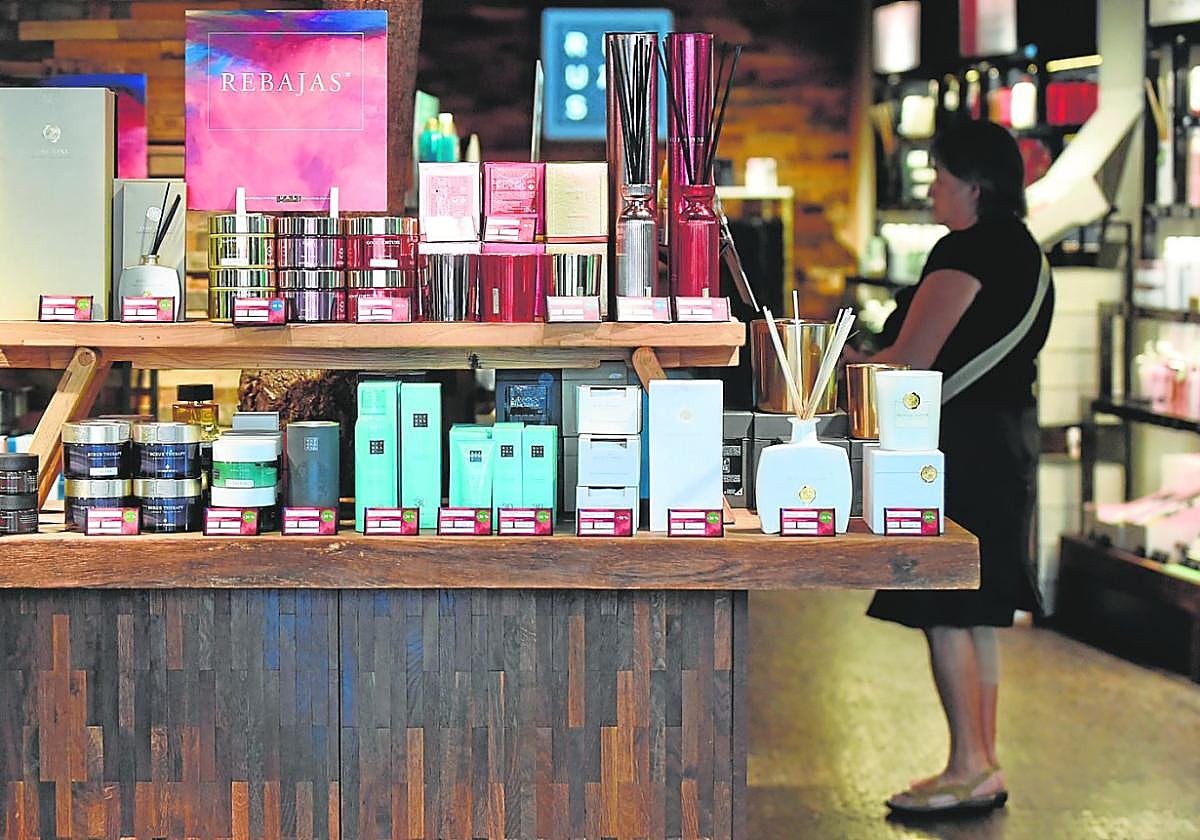 Una mujer examina los precios de los productos en rebajas en una tienda de cosméticos.