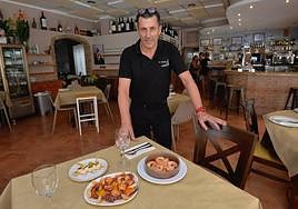 Alberto 'El Rapao' con los platos de pulpo y gambas al ajillo en su restaurante El Caldero, en el Club de Regatas del puerto de Mazarrón.
