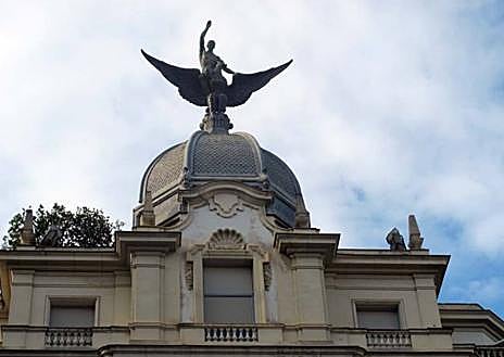Imagen secundaria 1 - La escultura del Ave Fénix que preside el edificio de la aseguradora 'La Unión y el Fénix', en la plaza de Santa Catalina; y un antiguo grabado que representa el Ave Fénix.