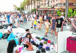 Vendedores ambulantes ofrecen su mercancía en el paseo de Torrevieja, abarrotado de turistas.