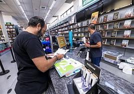 Un padre compra los libros de texto de su hijo para este curso, este lunes, en una librería de Murcia.