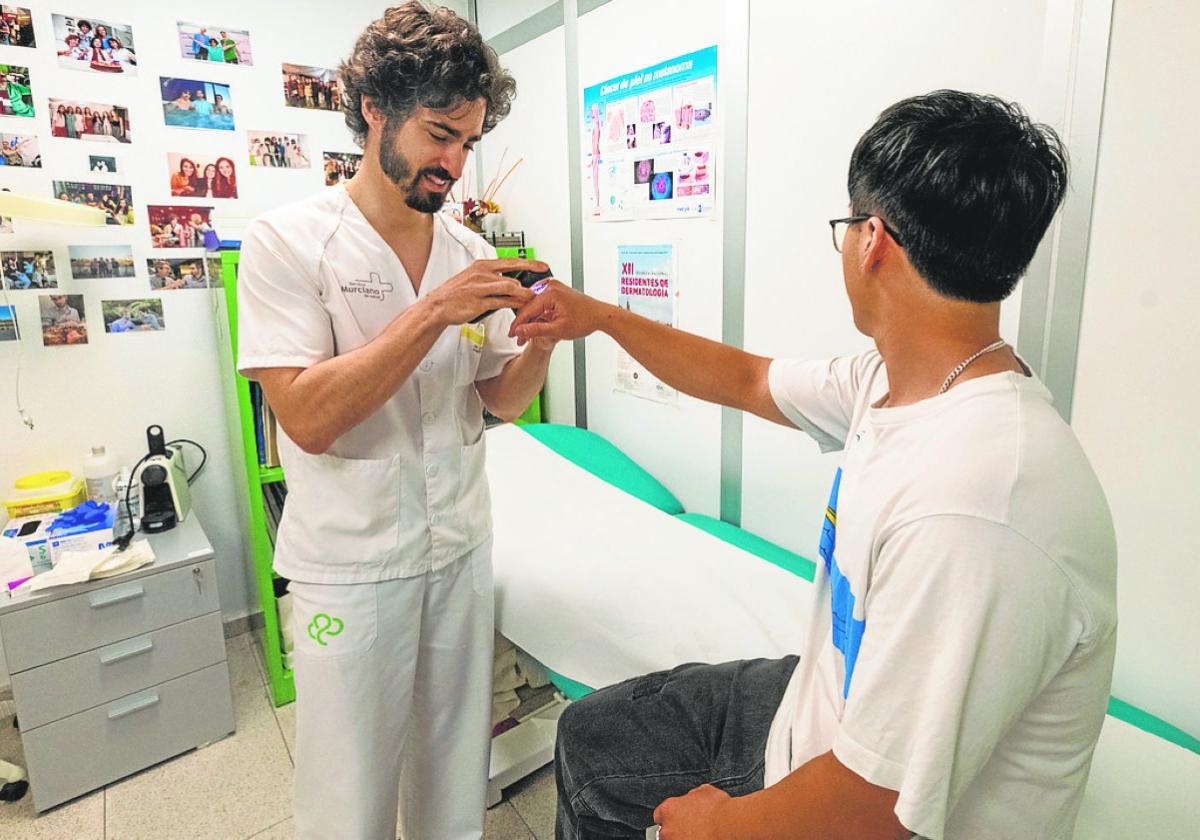 José Navarro estudia la piel de un paciente con un dermatoscopio en su consulta del Reina Sofía.