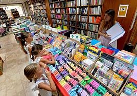 Pilar Molina Guillén muestra material escolar a sus tres hijas en la librería Diego Marín.